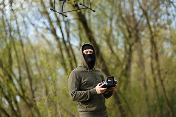 Image showing Man in mask operating a drone with remote control.