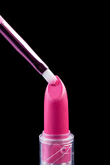 Image showing Tube of lipstick with a brush make-up on black 