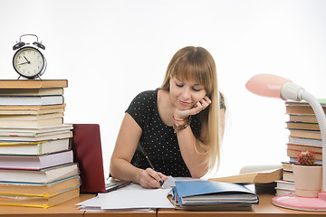 Image showing college student smiling engaged at the table cluttered with books in the library