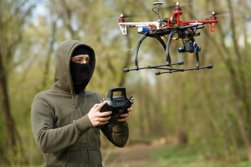 Image showing Man in mask operating a drone with remote control.