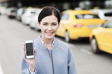 Image showing smiling woman showing smartphone over taxi in city