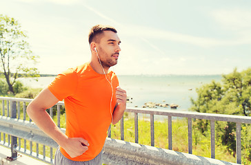 Image showing happy man with earphones running outdoors