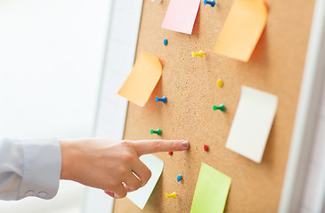 Image showing hand pointing to cork board with stickers and pins