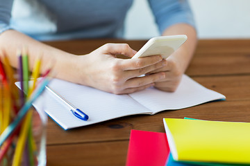 Image showing close up of student with smartphone and notebook