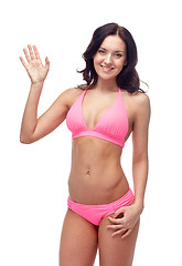 Image showing happy young woman in pink swimsuit waving hand