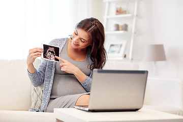 Image showing happy pregnant woman with ultrasound image at home