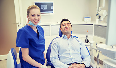 Image showing happy female dentist with man patient at clinic