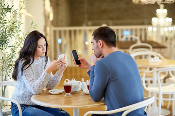 Image showing couple with smartphones drinking tea at cafe