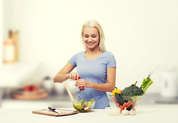 Image showing smiling woman cooking vegetable salad on kitchen