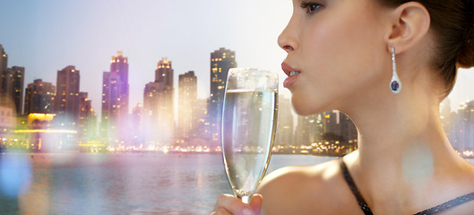 Image showing close up of woman drinking champagne in night city