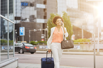 Image showing happy woman with travel bag calling on smartphone