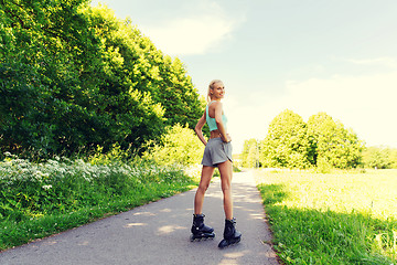 Image showing happy young woman in rollerskates riding outdoors