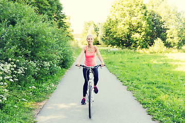 Image showing happy young woman riding bicycle outdoors