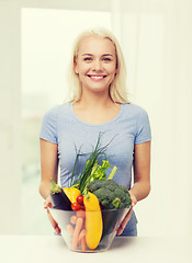 Image showing smiling young woman with vegetables at home