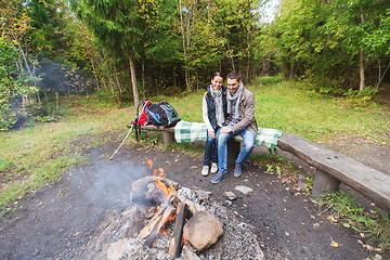 Image showing happy couple sitting on bench near camp fire