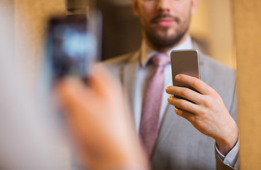 Image showing close up of man in suit taking mirror selfie