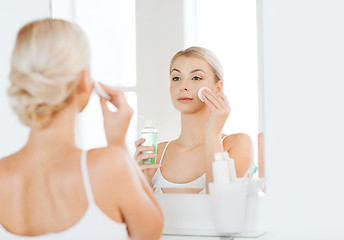Image showing young woman with lotion washing face at bathroom