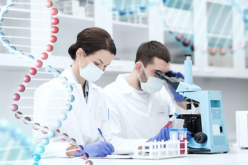 Image showing scientists with clipboard and microscope in lab