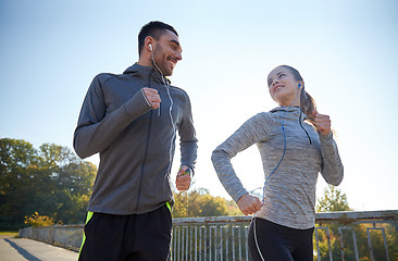 Image showing happy couple with earphones running outdoors