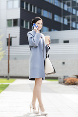 Image showing happy businesswoman calling on smartphone in city 