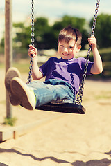 Image showing happy little boy swinging on swing at playground