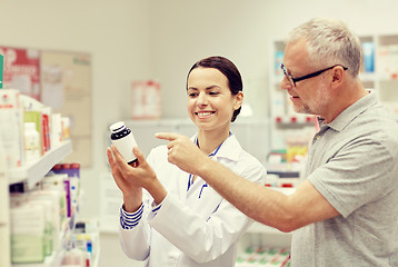 Image showing pharmacist showing drug to senior man at pharmacy