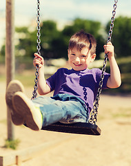 Image showing happy little boy swinging on swing at playground
