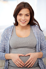 Image showing happy pregnant woman making heart gesture at home