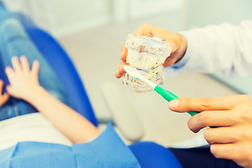 Image showing close up of dentist showing teeth maquette to girl