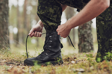 Image showing close up of soldier tying bootlaces in forest