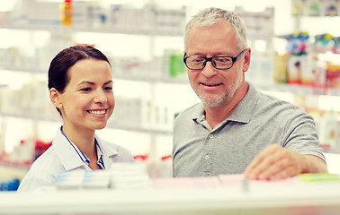 Image showing pharmacist showing drug to senior man at pharmacy