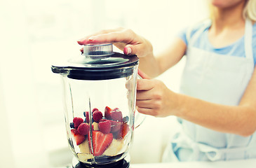 Image showing close up of woman with blender making fruit shake