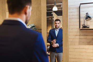 Image showing man trying jacket on at mirror in clothing store