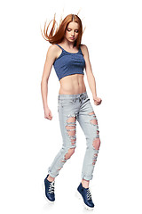 Image showing Modern red haired girl in distressed jeans jumping posing