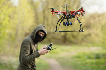 Image showing Man in mask operating a drone with remote control.