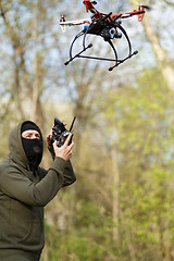 Image showing Man in mask operating a drone with remote control.