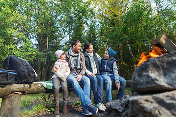 Image showing happy family sitting on bench at camp fire