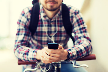 Image showing hipster man in earphones with smartphone and bike