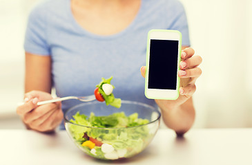 Image showing close up of woman with smartphone eating salad