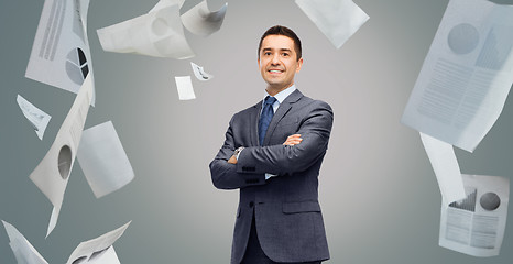 Image showing happy smiling businessman in suit over papers