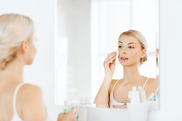 Image showing young woman with lotion washing face at bathroom