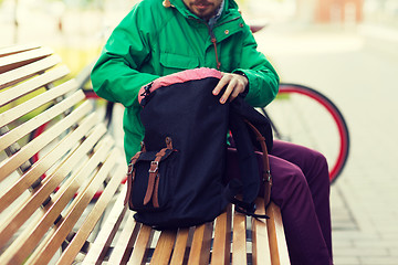 Image showing close up of man with backpack on city bench