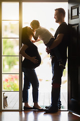 Image showing Young Son Kissing Pregnant Mom with Daddy in Doorway