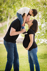 Image showing Pregnant Mixed Race Couple Kissing with Young Son Riding Piggyba