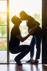 Image showing Mixed Race Pregnant Couple Kissing in Doorway.