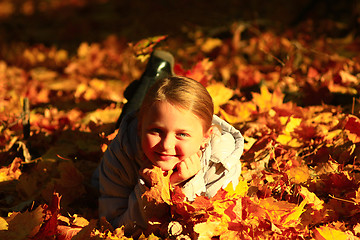 Image showing little girl laying in yellow leaves