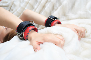 Image showing female hands in leather handcuffs. eagerly grabbed the sheets.. sex toys.