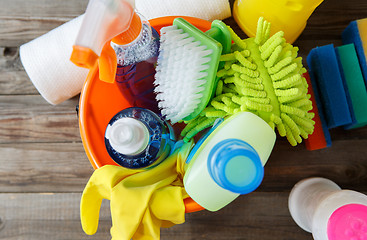Image showing Plastic bucket with cleaning supplies on wood background