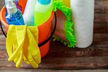 Image showing Plastic bucket with cleaning supplies on wood background