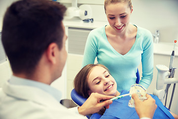 Image showing happy dentist showing toothbrush to patient girl